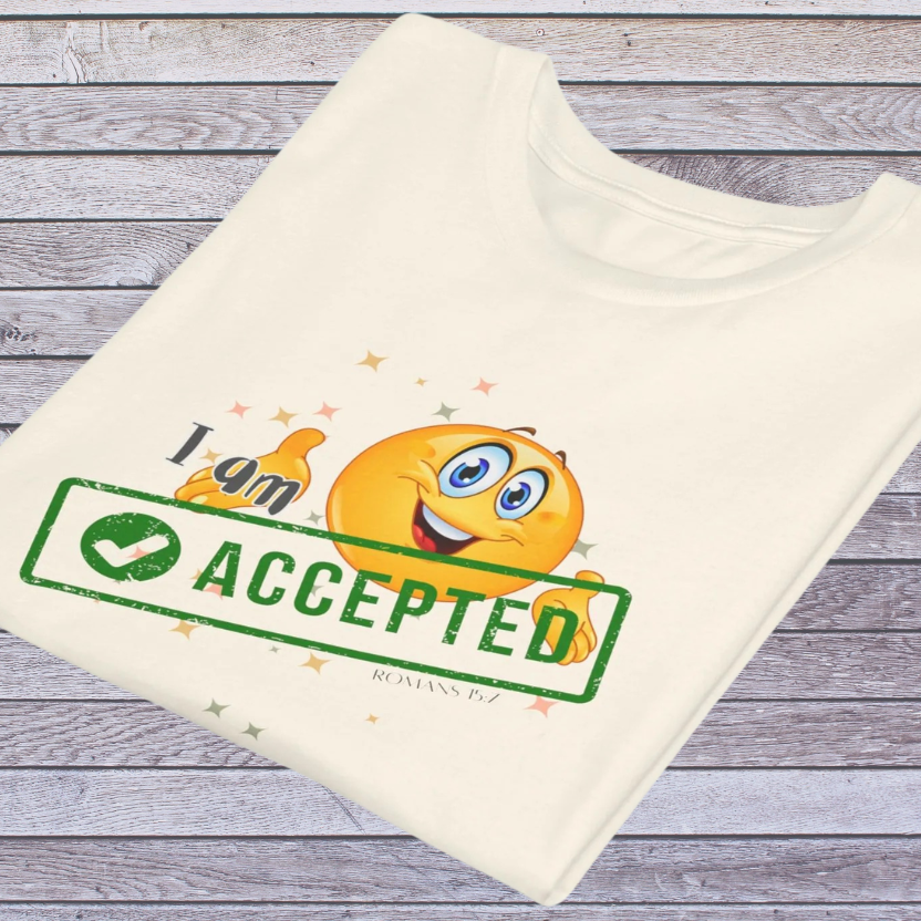 Natural colored t-shirt with emoji design and text 'I am accepted' on a wooden surface