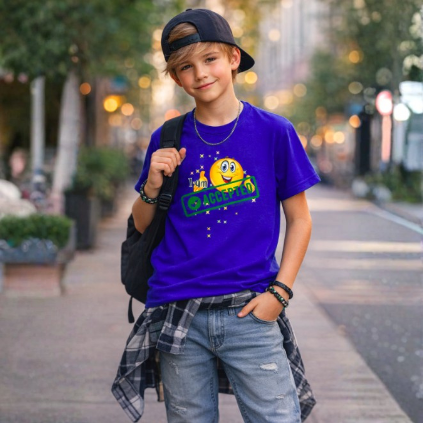 Young boy wearing a royal blue t-shirt with 'I am Accepted', standing on a street.