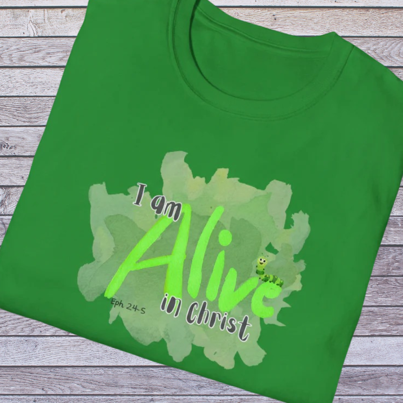 Green t-shirt with 'I am Alive in Christ' text on a wooden surface