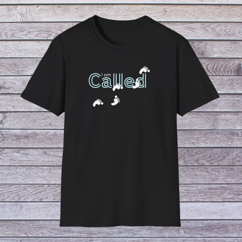 Black t-shirt with 'I am Called' text and footprints on a wooden background