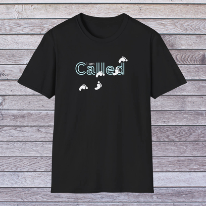 Black t-shirt with 'I am Called' text and footprints on a wooden background