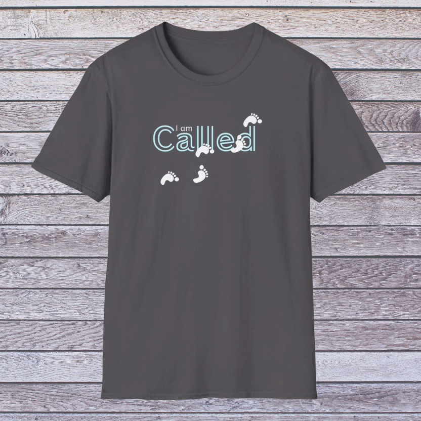 Dark gray t-shirt with 'I am Called' text and footprints on a wooden background