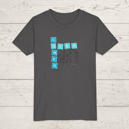 Gray t-shirt with blue and white graphic design 'Overcomer, 1 John 5:4' on a wooden surface