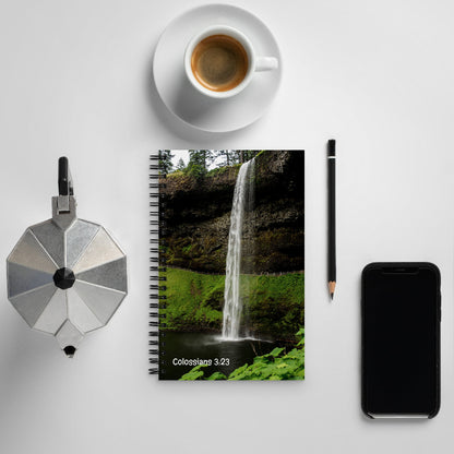 Notebook with waterfall design, coffee cup, pen, and phone on a light gray background
