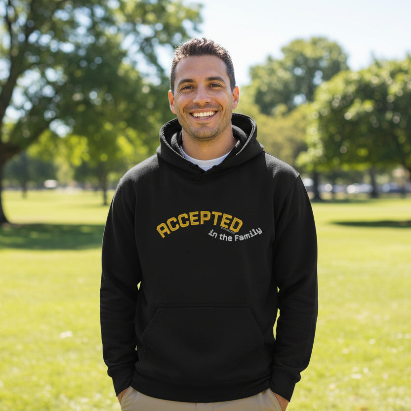 Black hoodie with yellow text 'Accepted in the Family' outside in park