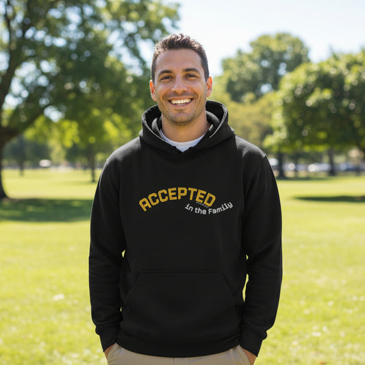 Black hoodie with yellow text 'Accepted in the Family' outside in park