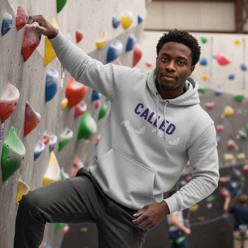 Gray hoodie with 'CALLED' text in purple with white footprints. Rock climbing.