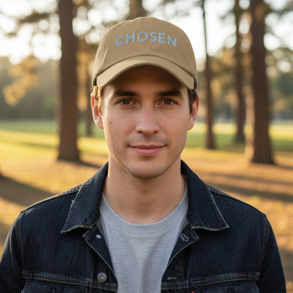 Brown cap with 'Chosen' embroidered on it, man wearing cap outside in the park