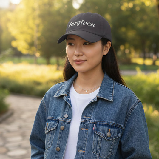 Black cap with 'Forgiven' embroidered on it standing outside in a park
