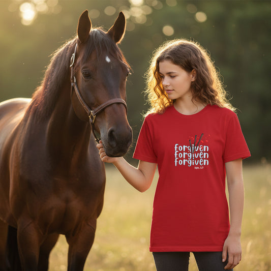 Red t-shirt with 'forgiven' text design next to a brown horse