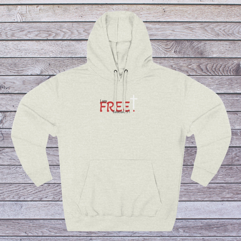 Oatmeal Heather Beige hoodie with red text on a wooden surface, 'I am free, Galatians'