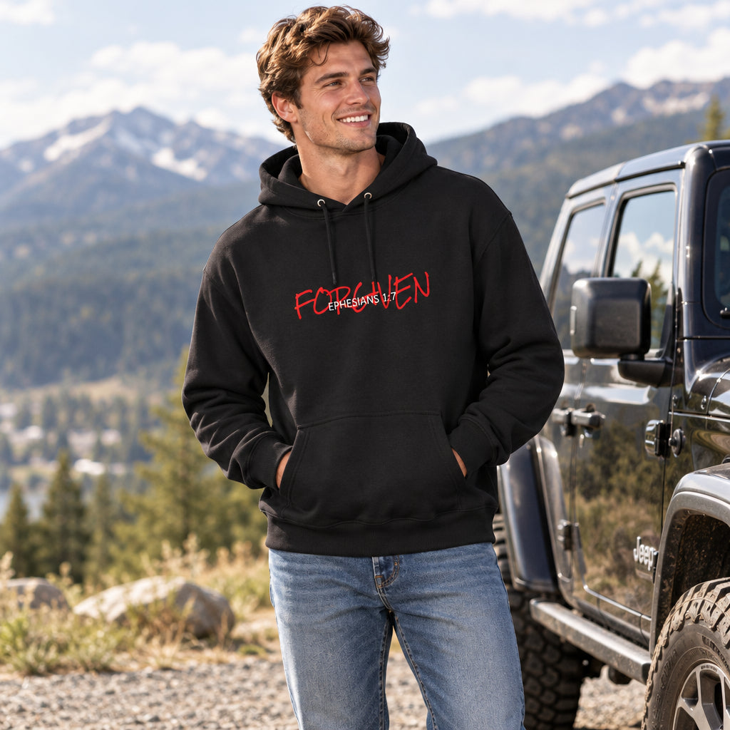 black pullover hoodie with words "forgiven, ephesians 1:7", worn by a male outside near jeep in the mountains. 