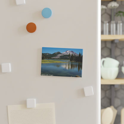 Canvas print of a mountain landscape hanging on a wall with decorative hooks.
