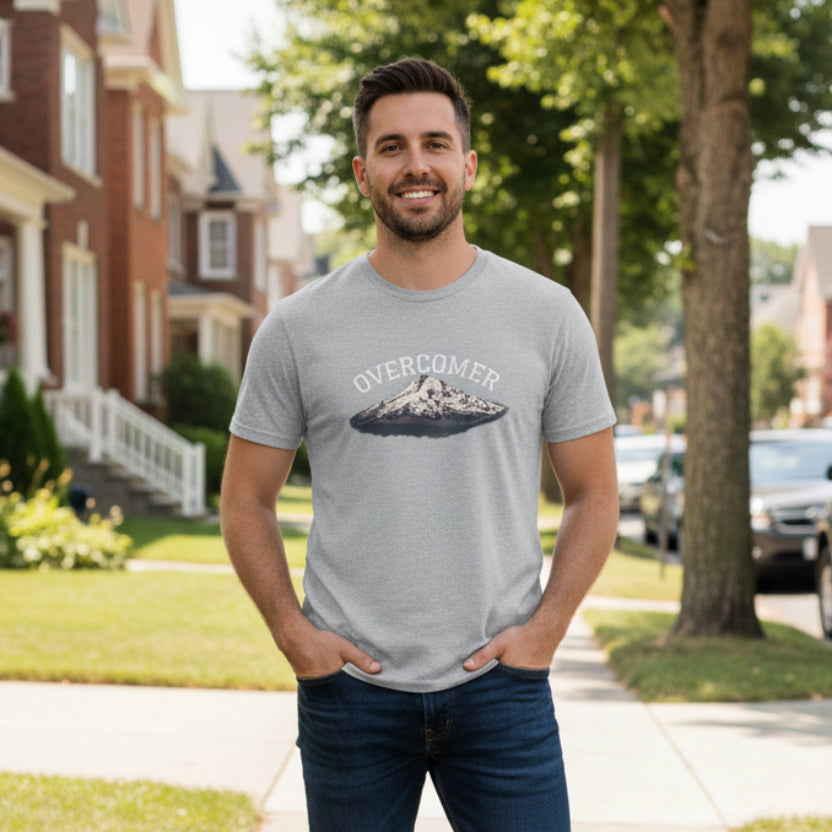Gray t-shirt with 'Overcomer' graphic design in the neighborhood of homes