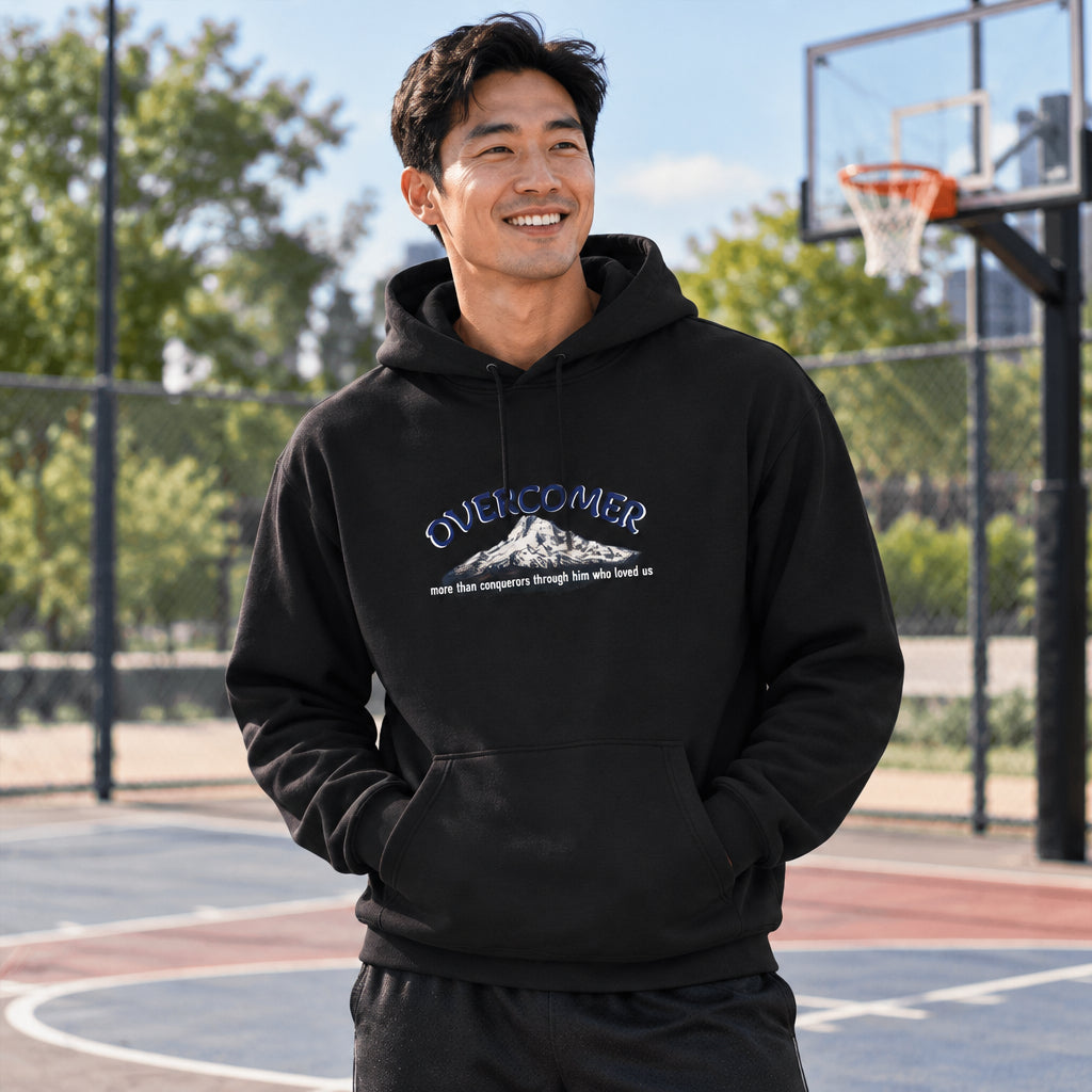 Man wearing a black hoodie with an overcomer design, standing outside on basketball court