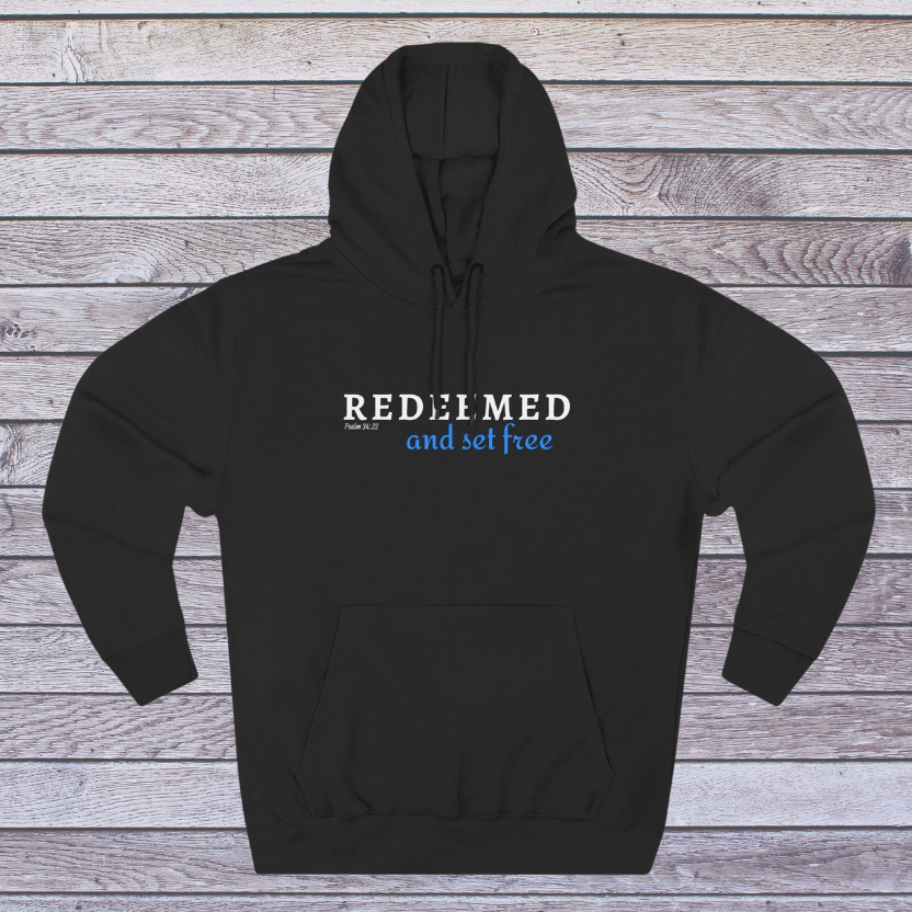Black hoodie with 'REDEEMED and set free' text on a wooden background