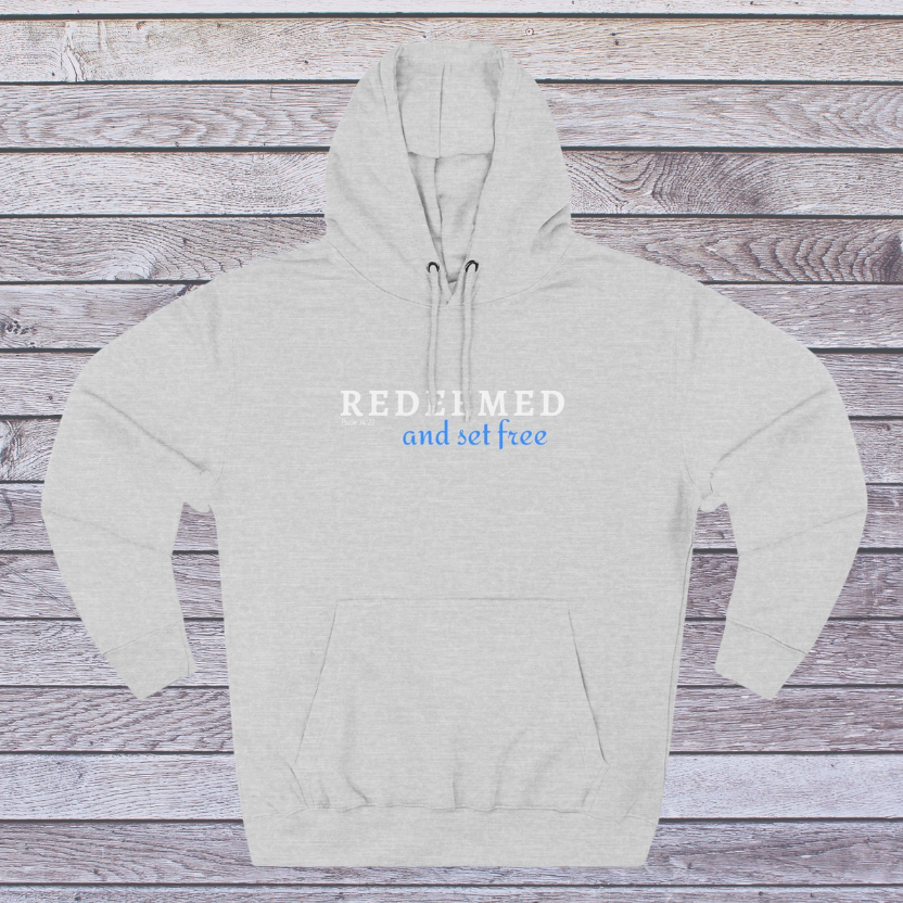 Gray hoodie with text 'REDEEMED and set free' on a wooden background