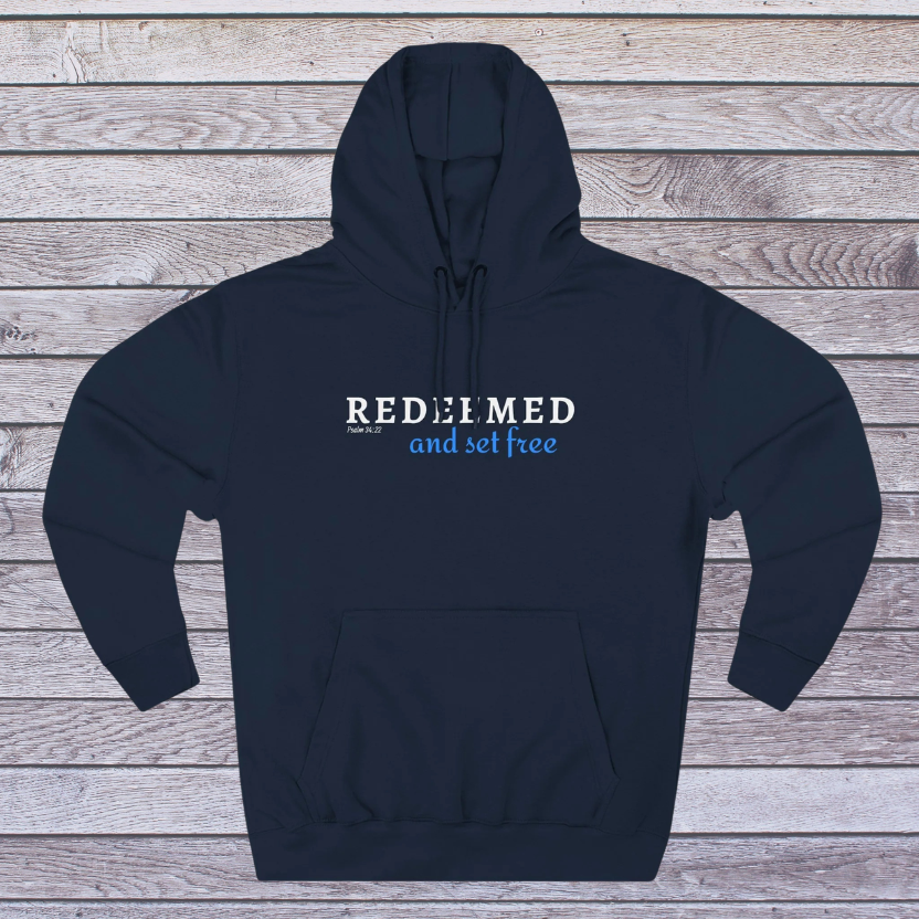 Navy hoodie with 'REDEEMED and set free' text on a wooden background