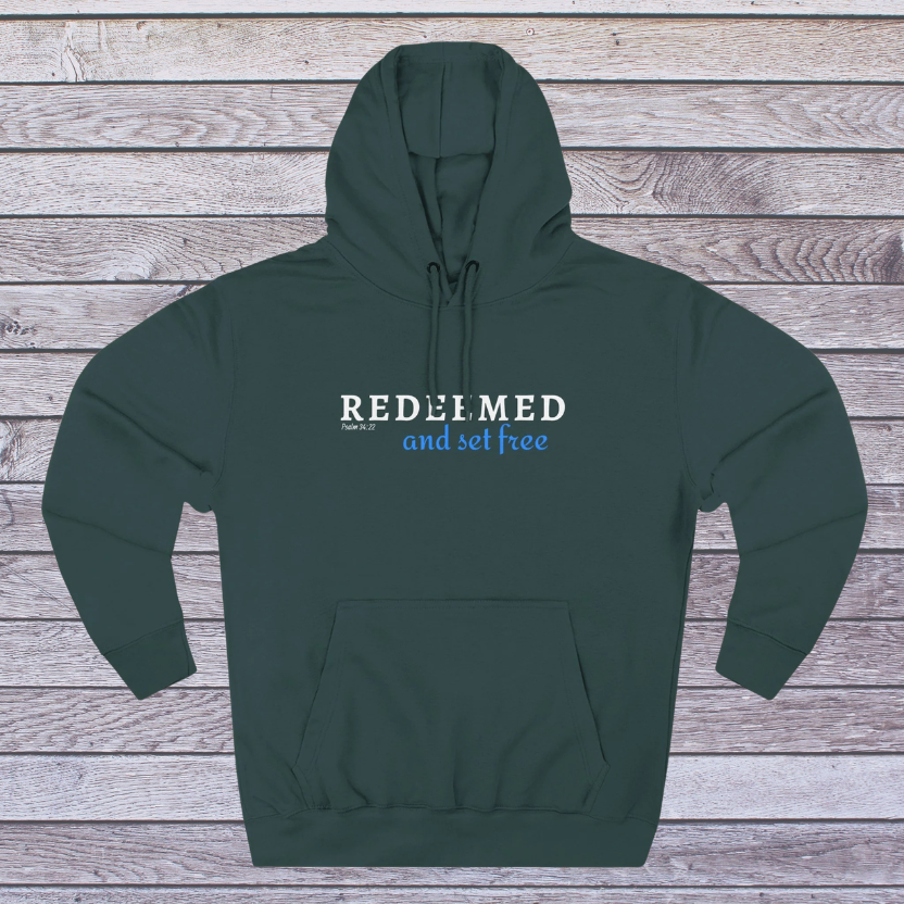 Green hoodie with 'REDEEMED and set free' text on a wooden background