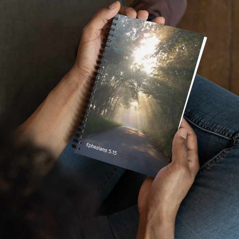 Person holding a notebook with a scenic cover and visible text.