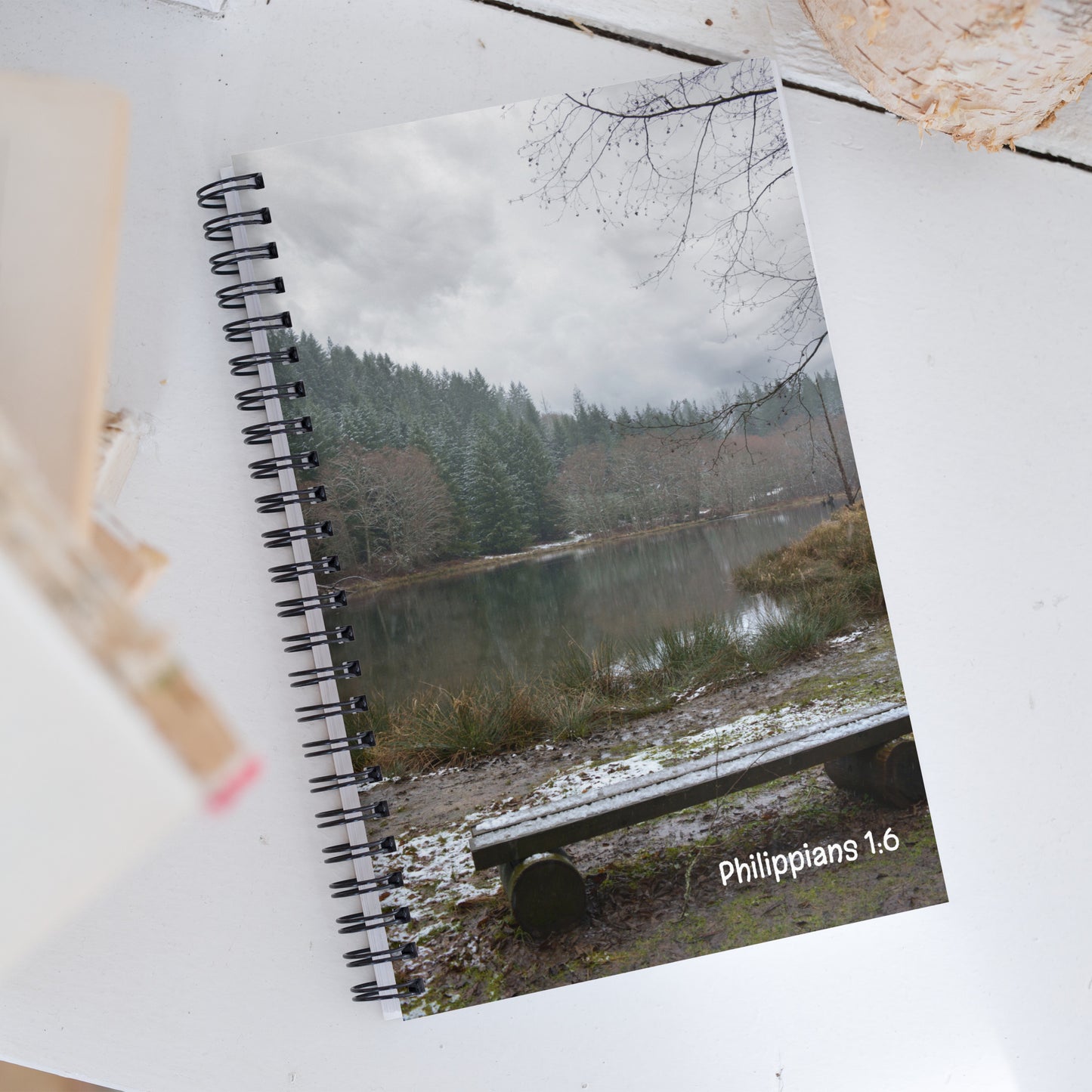 Notebook with a nature-themed cover featuring a lake and trees, placed on a wooden surface.