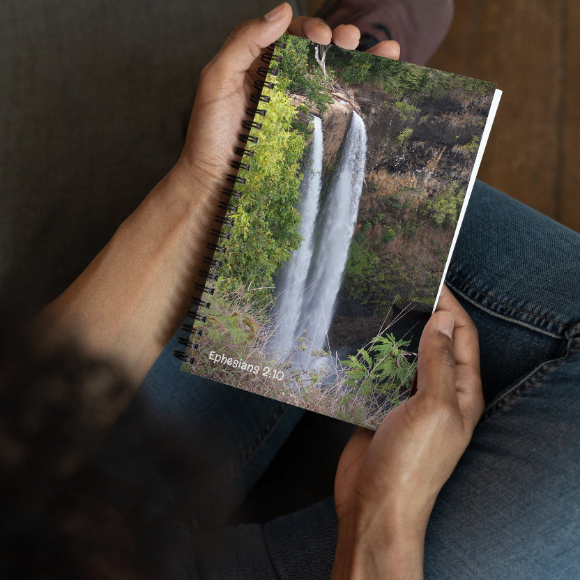 Person holding a notebook with a waterfall cover