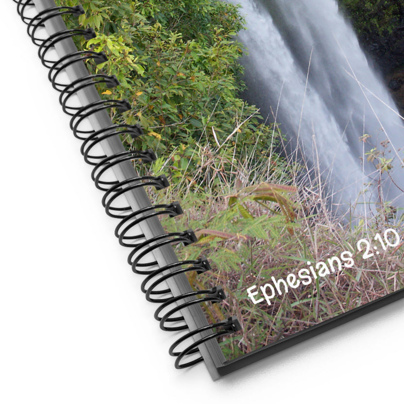 Notebook with spiral binding and 'Ephesians 2:10' text against a nature background