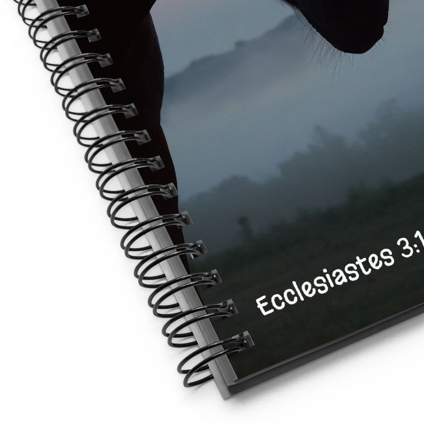 Spiral-bound notebook with 'Ecclesiastes 3:1' text on a reflective surface