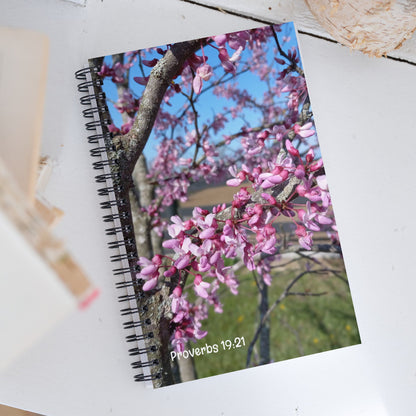 Notebook with a floral design on the cover, featuring pink blossoms and a tree branch.