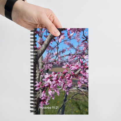 Notebook with a floral design on the cover held by a hand