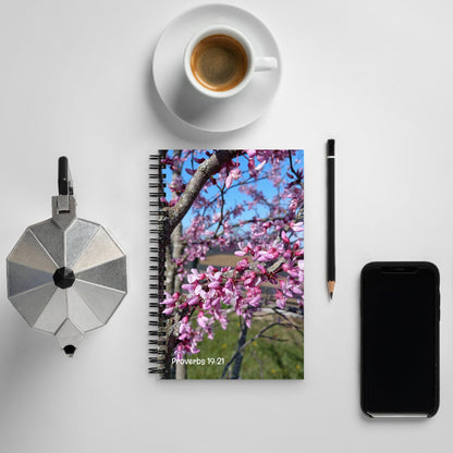 Notebook with cherry blossom design, coffee cup, pencil, and phone on a light gray surface