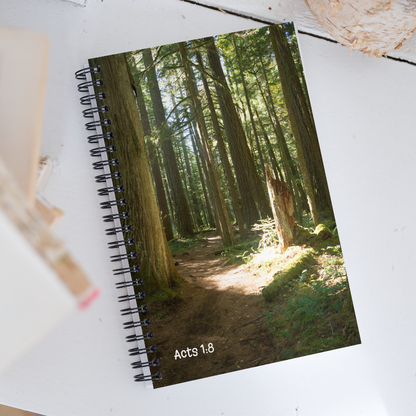 Notebook with a forest cover and 'Acts 1:8' text on a white surface