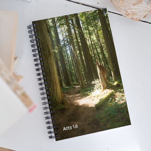 Notebook with a forest cover and 'Acts 1:8' text on a white surface