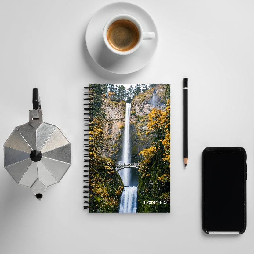 Notebook with waterfall design, coffee cup, pencil, and phone on a white surface
