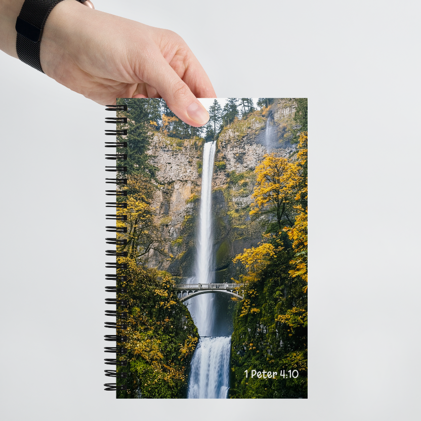 Notebook with a waterfall design held by a hand on a light gray background