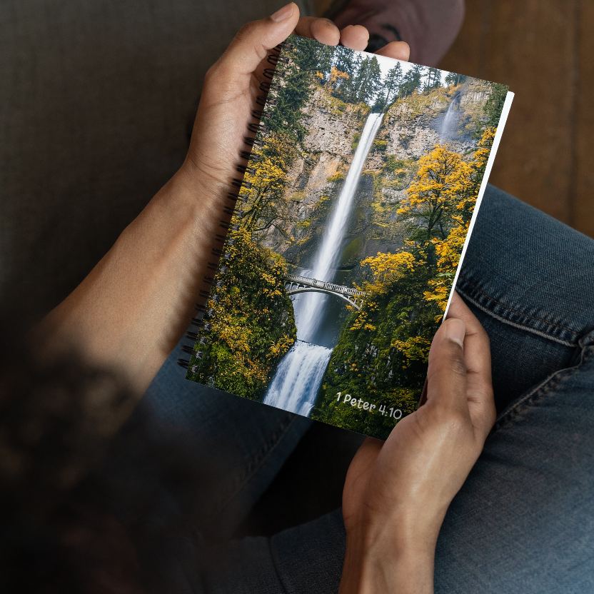 Person holding a notebook with a waterfall design and text on the cover.