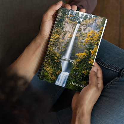Person holding a notebook with a waterfall design and text on the cover.