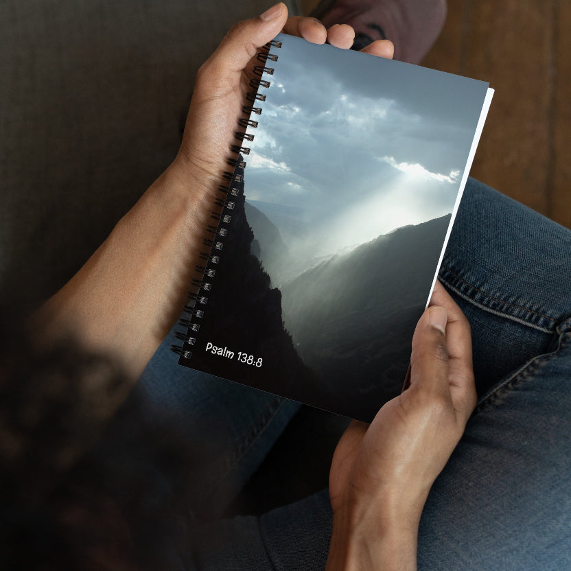 Person holding a notebook with a mountain landscape cover