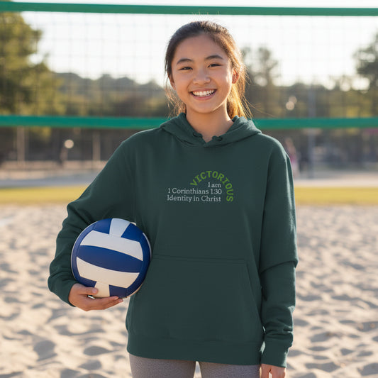 Green hoodie with a 'I am Victorious, 1 Corinthians 15:57, Identity in Christ' design, holding volleyball on the sand