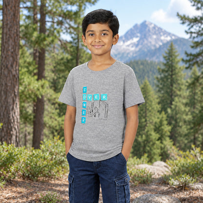 A young boy wearing a heather gray t-shirt with graphic print that reads 'overcomer', paired with dark blue jeans, photographed outside